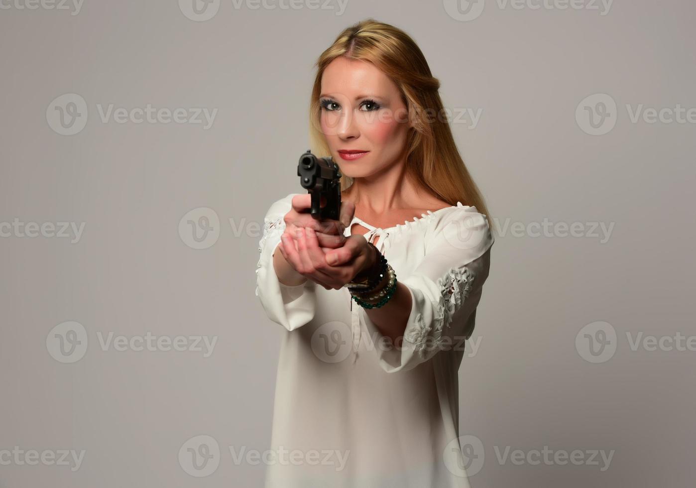 bela agente secreta em vestido preto segurando revólver, isolada no branco foto
