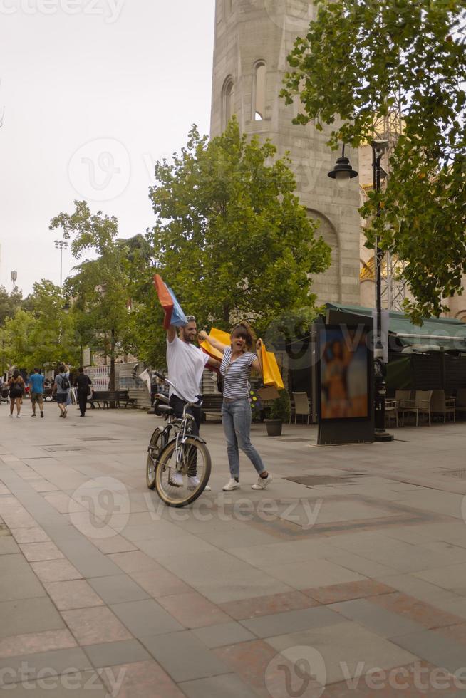 retrato de um jovem casal caucasiano alegre homem e mulher segurando muitos sacos de papel depois de fazer compras enquanto caminhava e conversava na rua. casal de família feliz com pacotes ao ar livre. conceito de compra foto