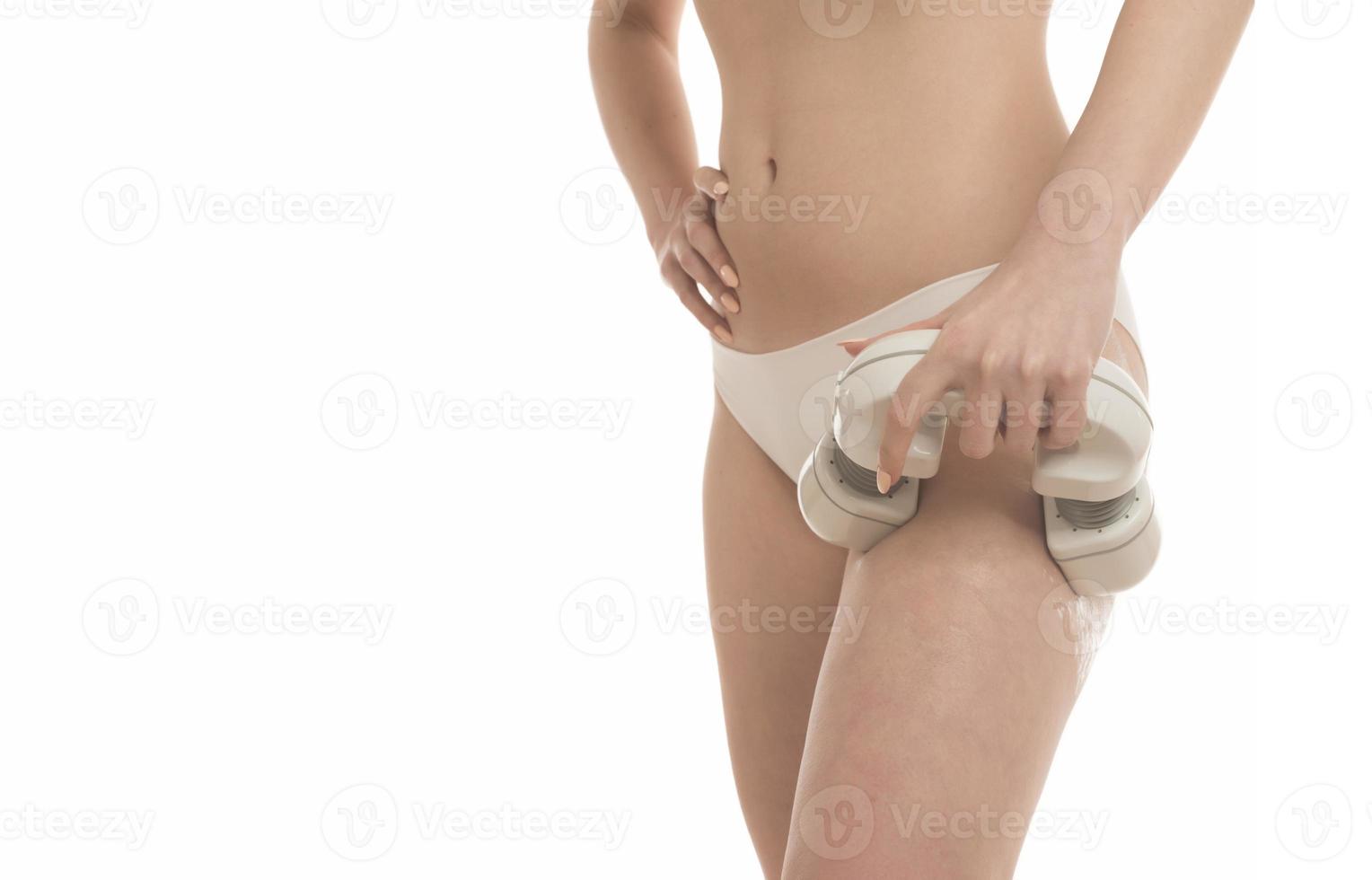 mulher desconhecida com corpo de forma perfeita vestindo cueca branca massageando os quadris com massageador elétrico. isolado no fundo branco foto