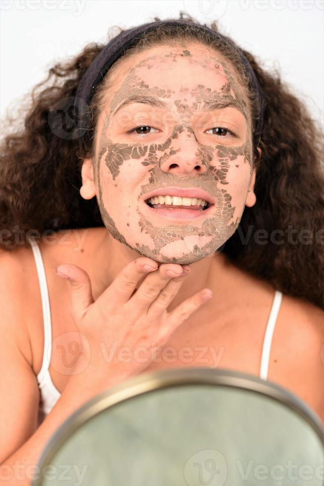 linda mulher removendo máscara facial de argila do rosto foto