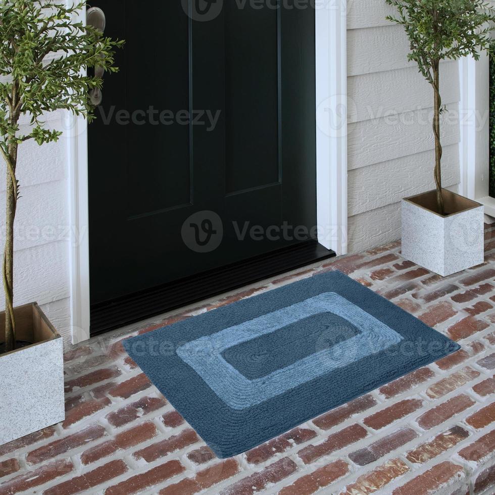 capacho de entrada de boas-vindas de design colocado no piso de tijolo sólido do lado de fora da porta de entrada com plantas foto