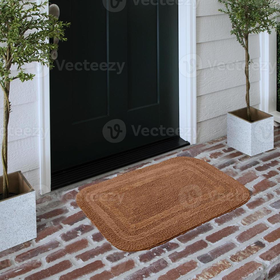 capacho de entrada de boas-vindas de design colocado no piso de tijolo sólido do lado de fora da porta de entrada com plantas foto