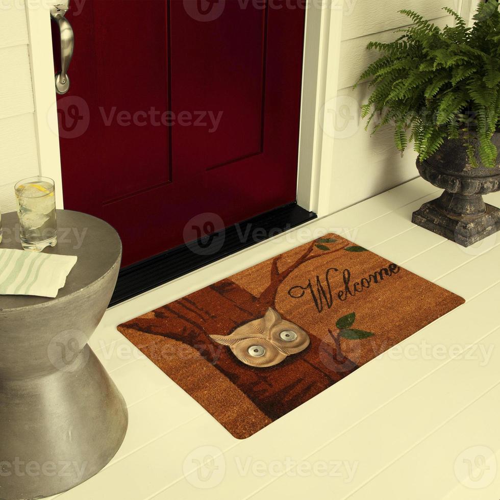 capacho de entrada de boas-vindas de design colocado no chão do lado de fora da porta de entrada com plantas e bebida gelada de limão foto