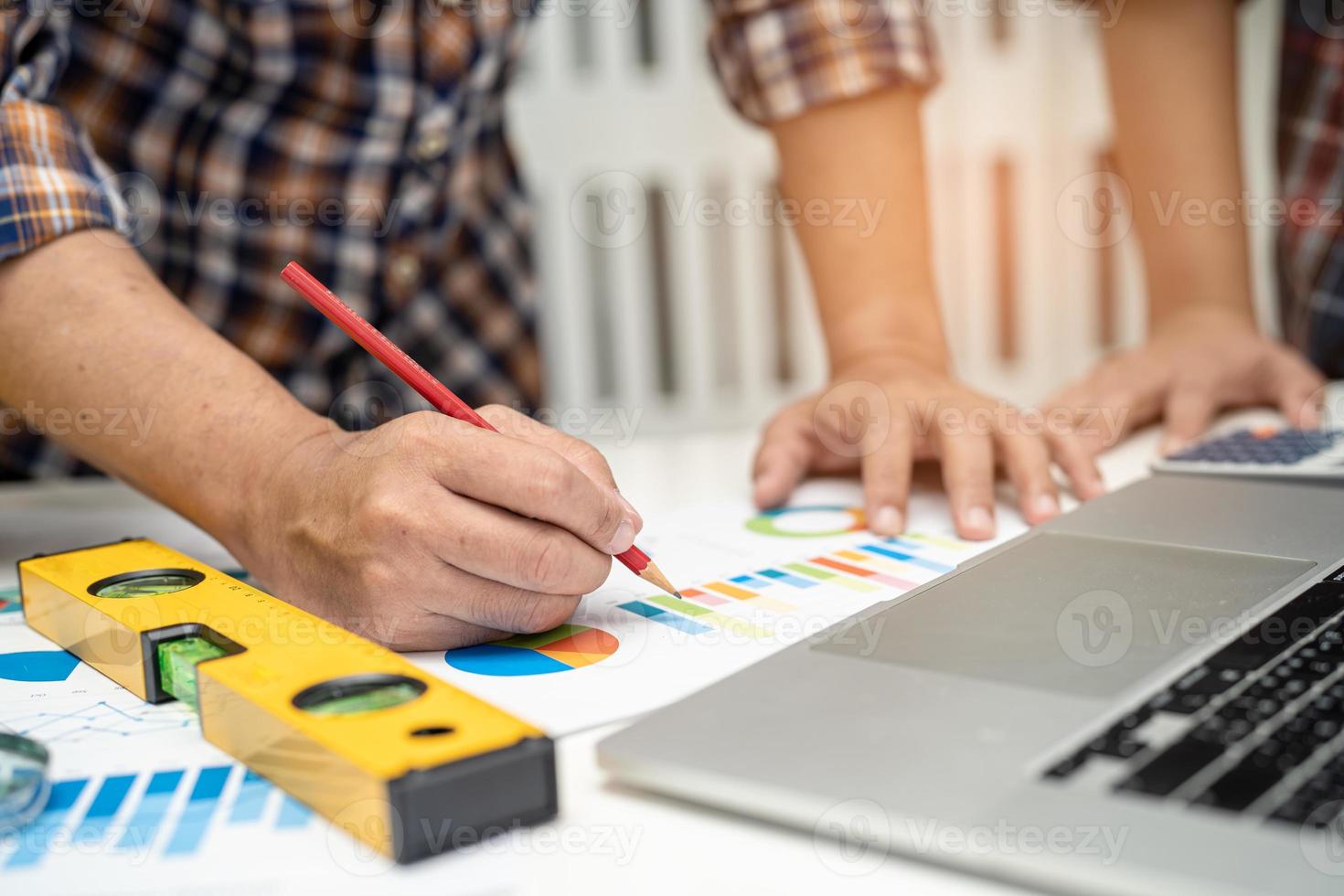 engenheiro asiático e equipe parceira aprendem e conversam com o projeto do plano da casa, gráfico e capacete amarelo e ferramentas de construção de engenharia no trabalho de mesa. foto