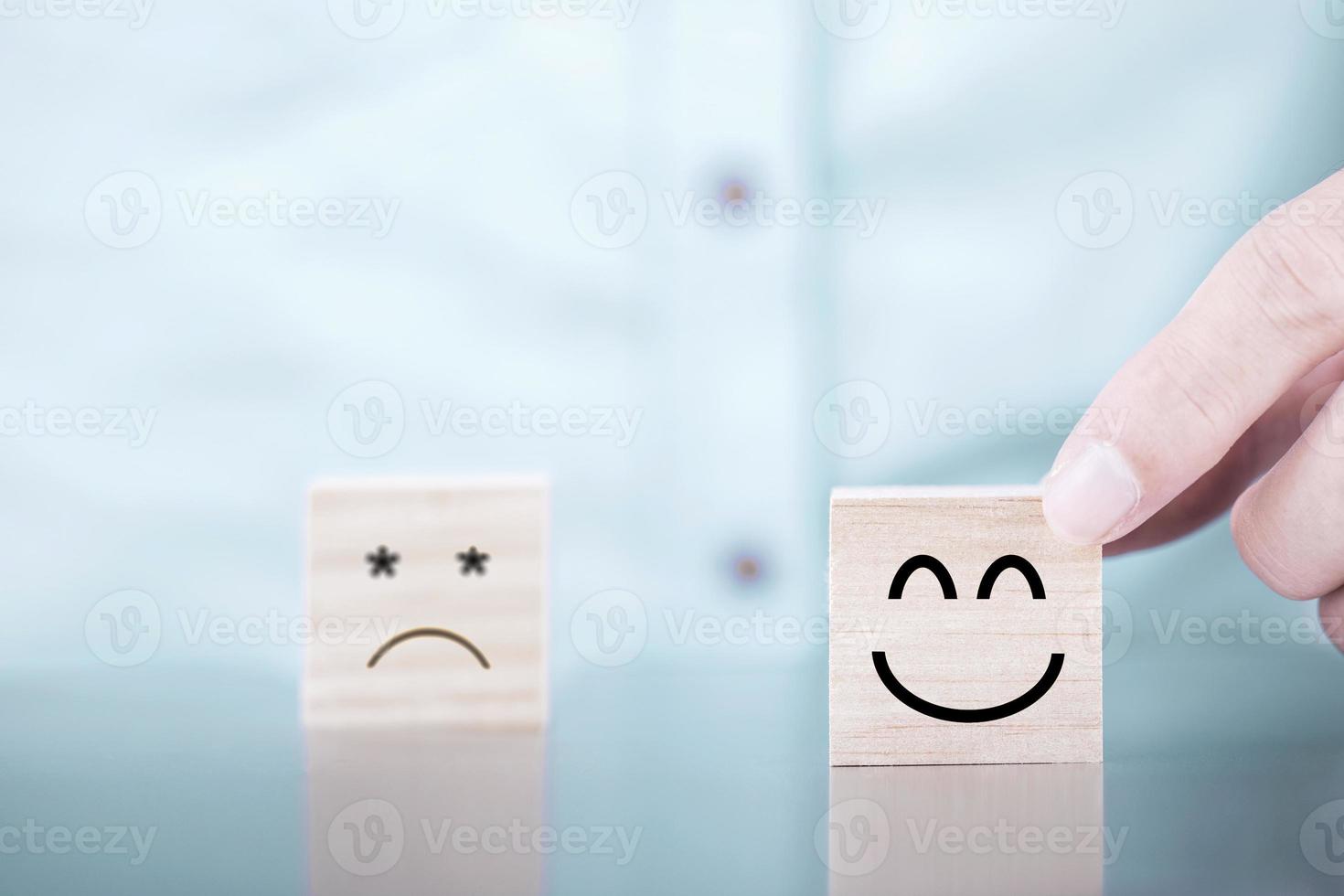 empresário escolhe um ícone de emoticon de sorriso rosto símbolo feliz no bloco de madeira, serviços e conceito de pesquisa de satisfação do cliente foto