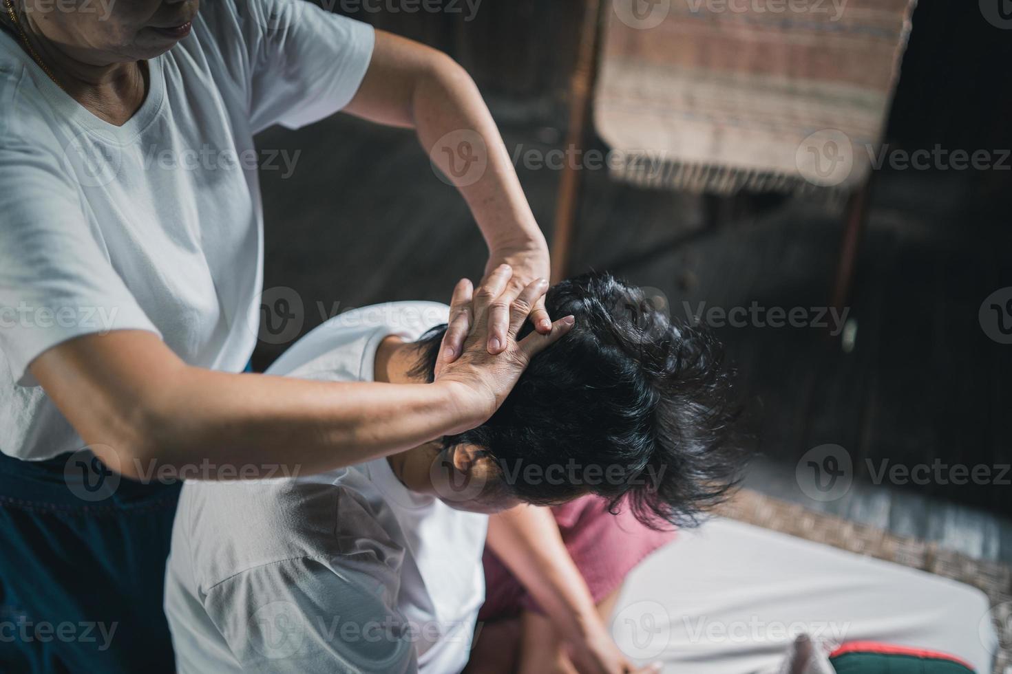 massagem e spa tratamento relaxante da síndrome do escritório estilo tradicional de massagem tailandesa. asain massagista feminina sênior fazendo massagem trata a cabeça, dor nas costas, dor no braço, pé e estresse para a velha cansada. foto