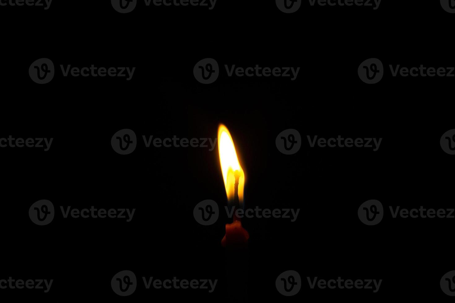 um close-up de uma vela acesa com chama amarela, uma luz de vela no escuro, ela queima e depois de um tempo uma rajada de vento a apaga. foto