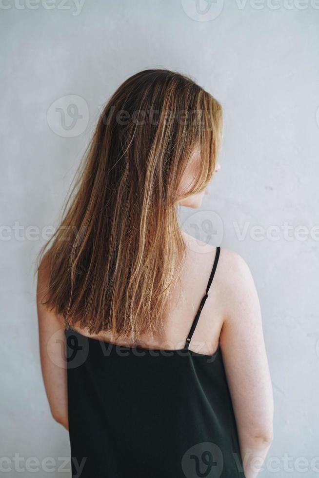 retrato de jovem com cabelos longos na noite elegante vestido preto de volta no interior branco foto