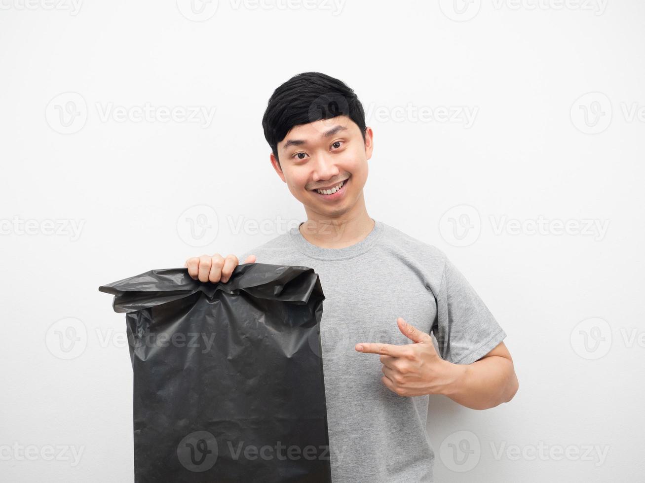 homem sorrindo e apontando o dedo para o lixo na mão fundo branco foto