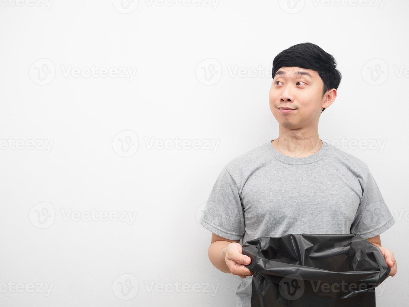 homem asiático segurando lixo e olhando para o espaço da cópia foto