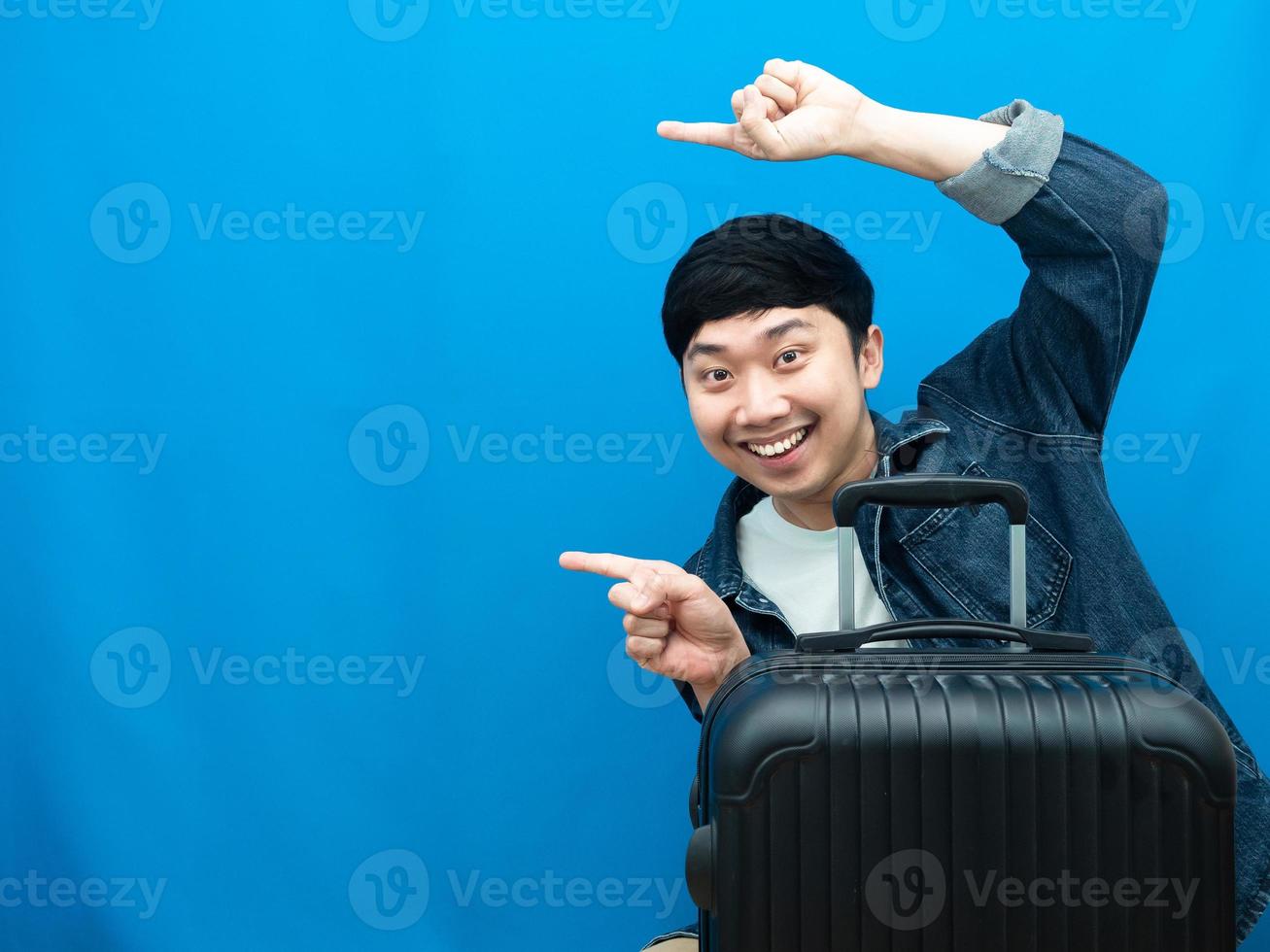 homem com bagagem, gesto sorridente, apontar o dedo para o conceito de férias de espaço de cópia foto