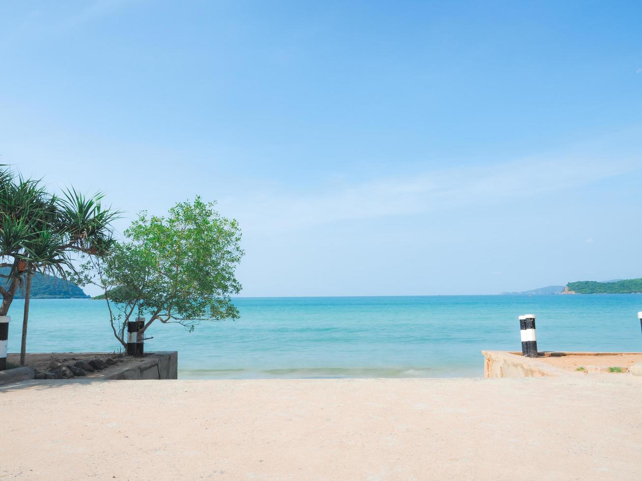 bela praia com céu azul oceano azul e paisagem de vista para a montanha e luz solar brilhante na imagem do conceito de férias foto