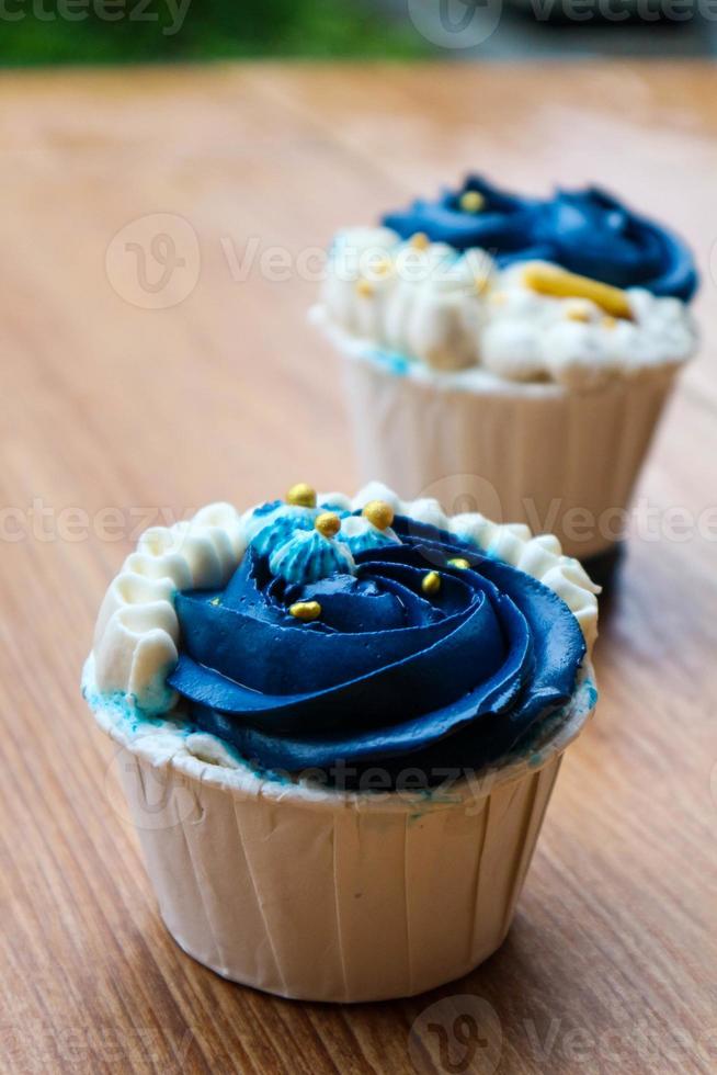 cupcakes luxuosos e elegantes, com creme branco e azul marinho com granulado dourado. foto