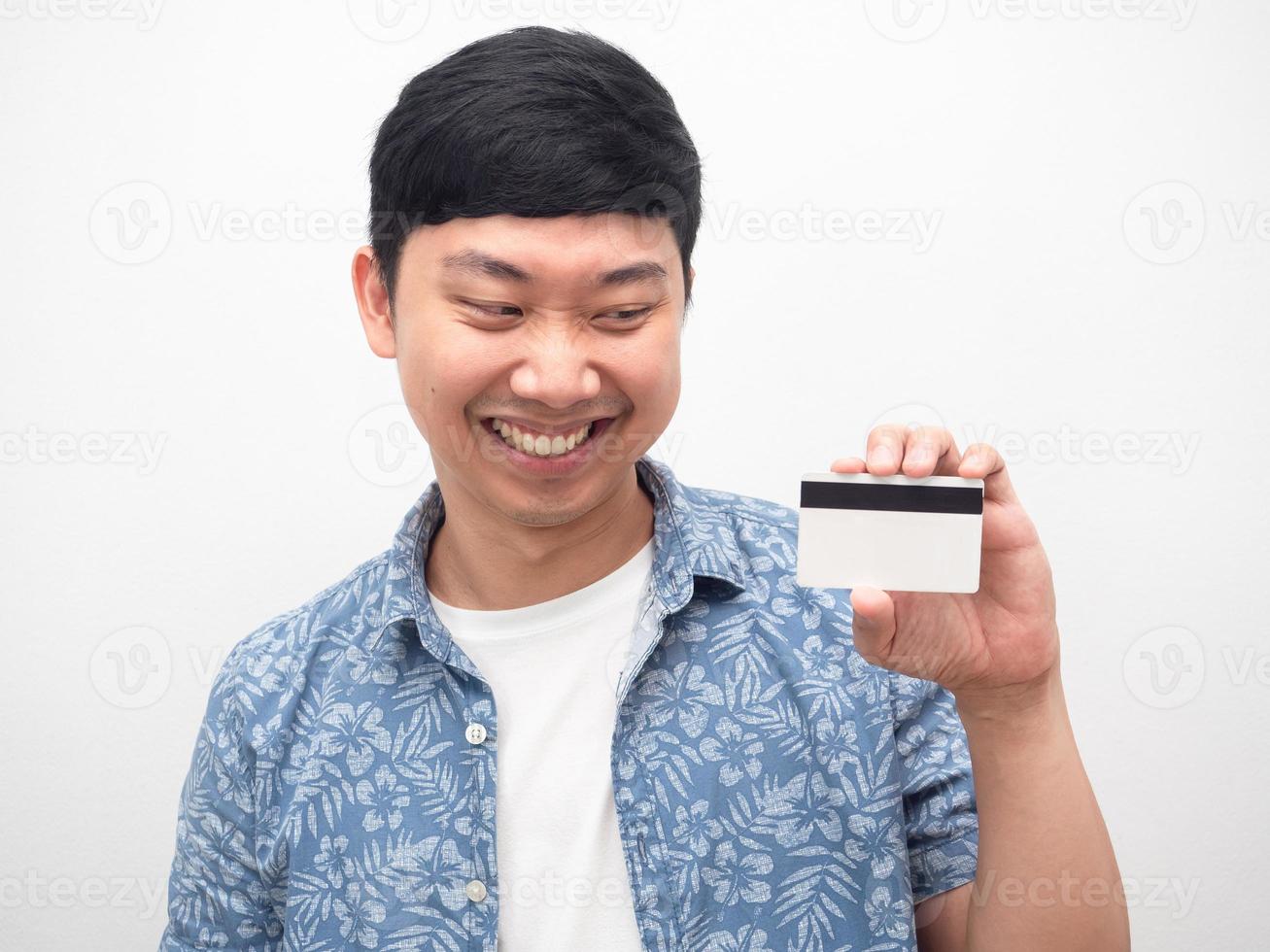 feche o homem olhando para o cartão de crédito na mão, sorrindo e alegre foto