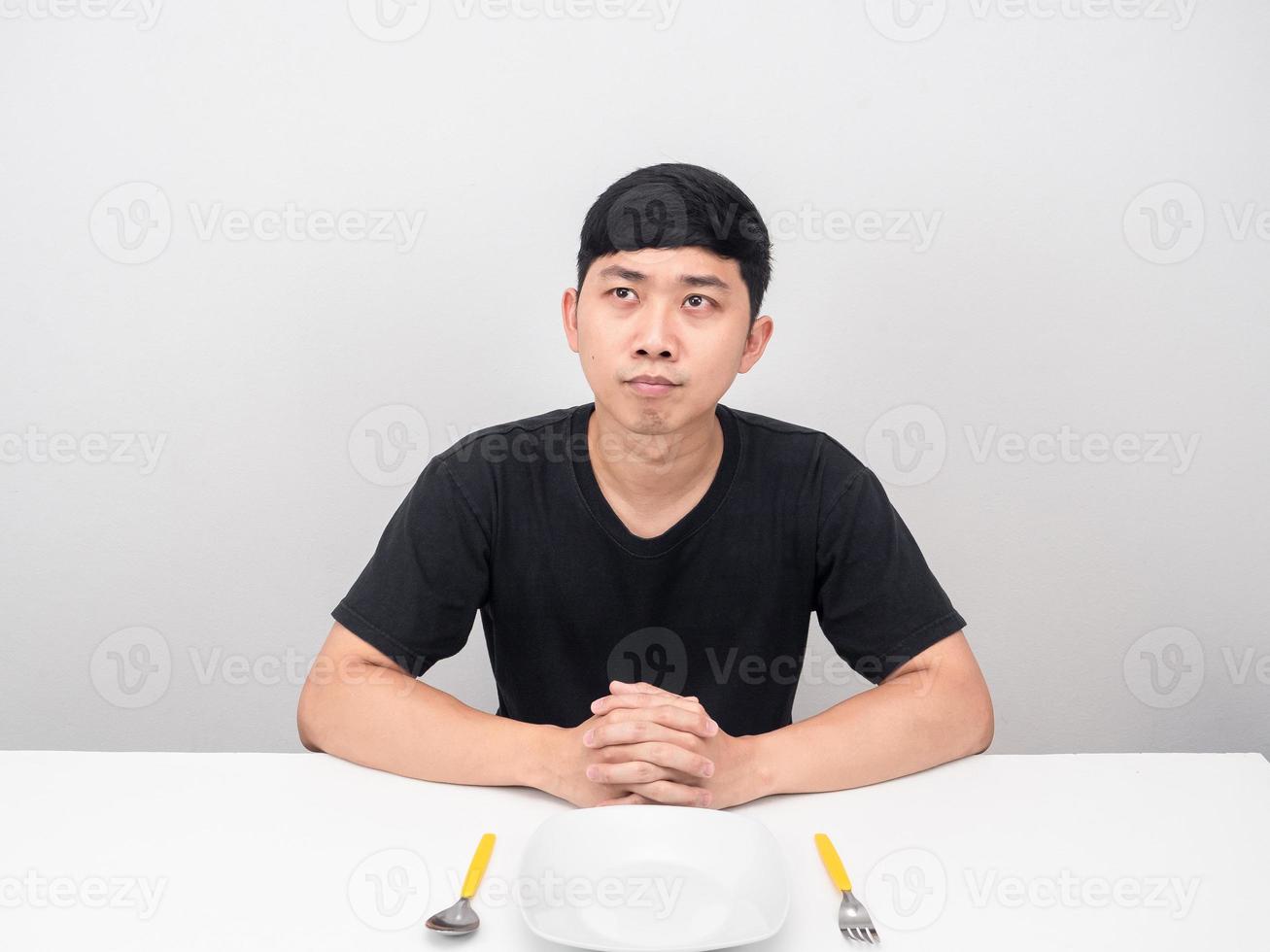 homem asiático sente-se à mesa pensando em comida foto
