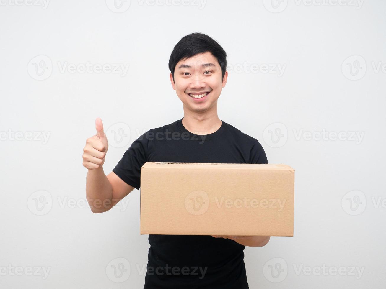 homem segurando a caixa de encomendas e mostrando o polegar para cima sorriso feliz foto