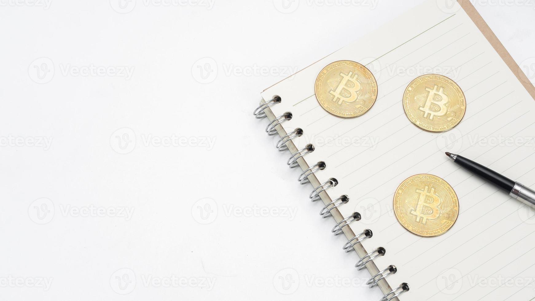 bitcoin com caneta no caderno de página em branco no espaço de cópia da vista superior da mesa foto