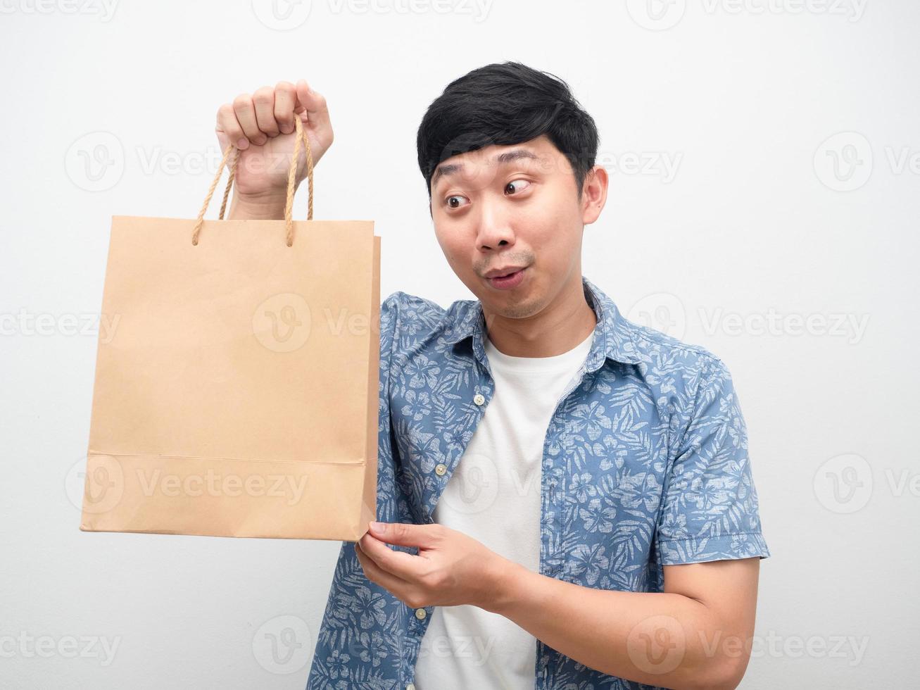 homem asiático camisa azul olhando para a sacola de compras na mão emoção excitada foto