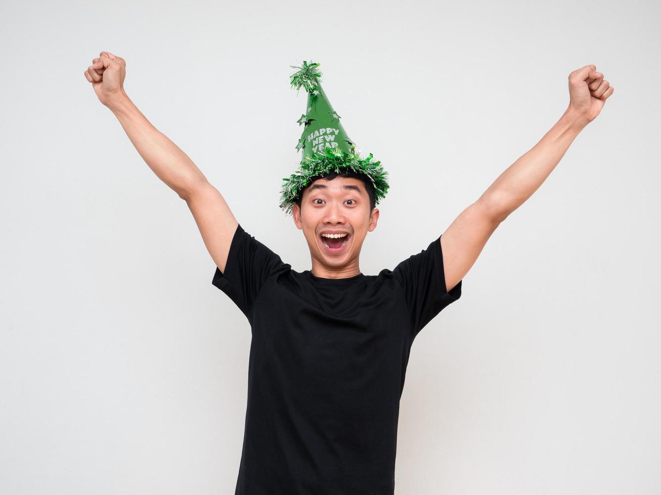 jovem olhar feliz e alegre para câmera mostra braço e punho com chapéu verde e borla colorida em branco isolado feliz ano novo celebração do conceito foto