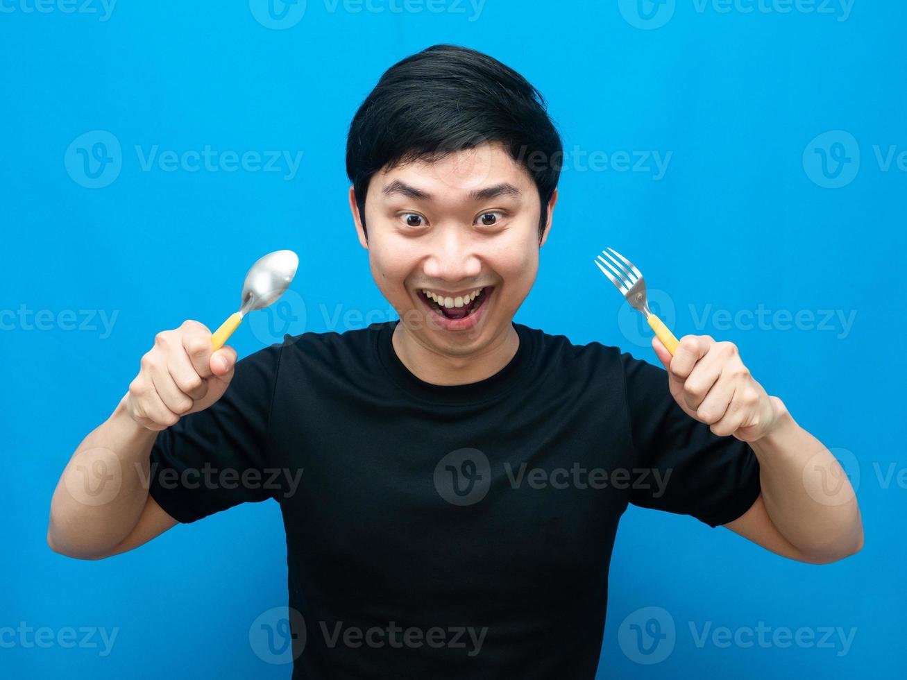 homem segurando o gesto de talheres comendo comida e olhando para o fundo azul foto