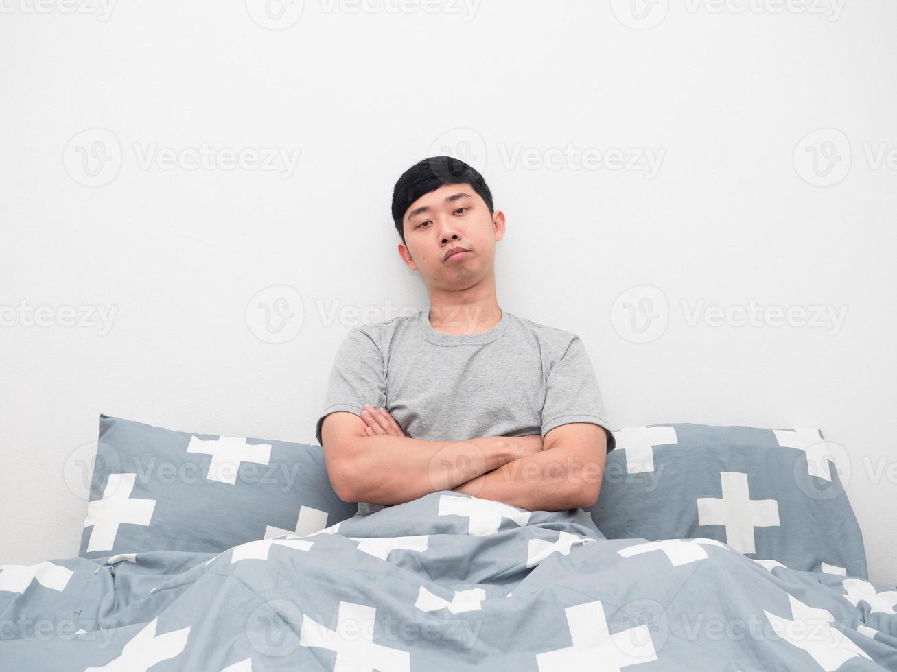 homem sentado na cama gesto cruzando o braço sentindo-se entediado foto
