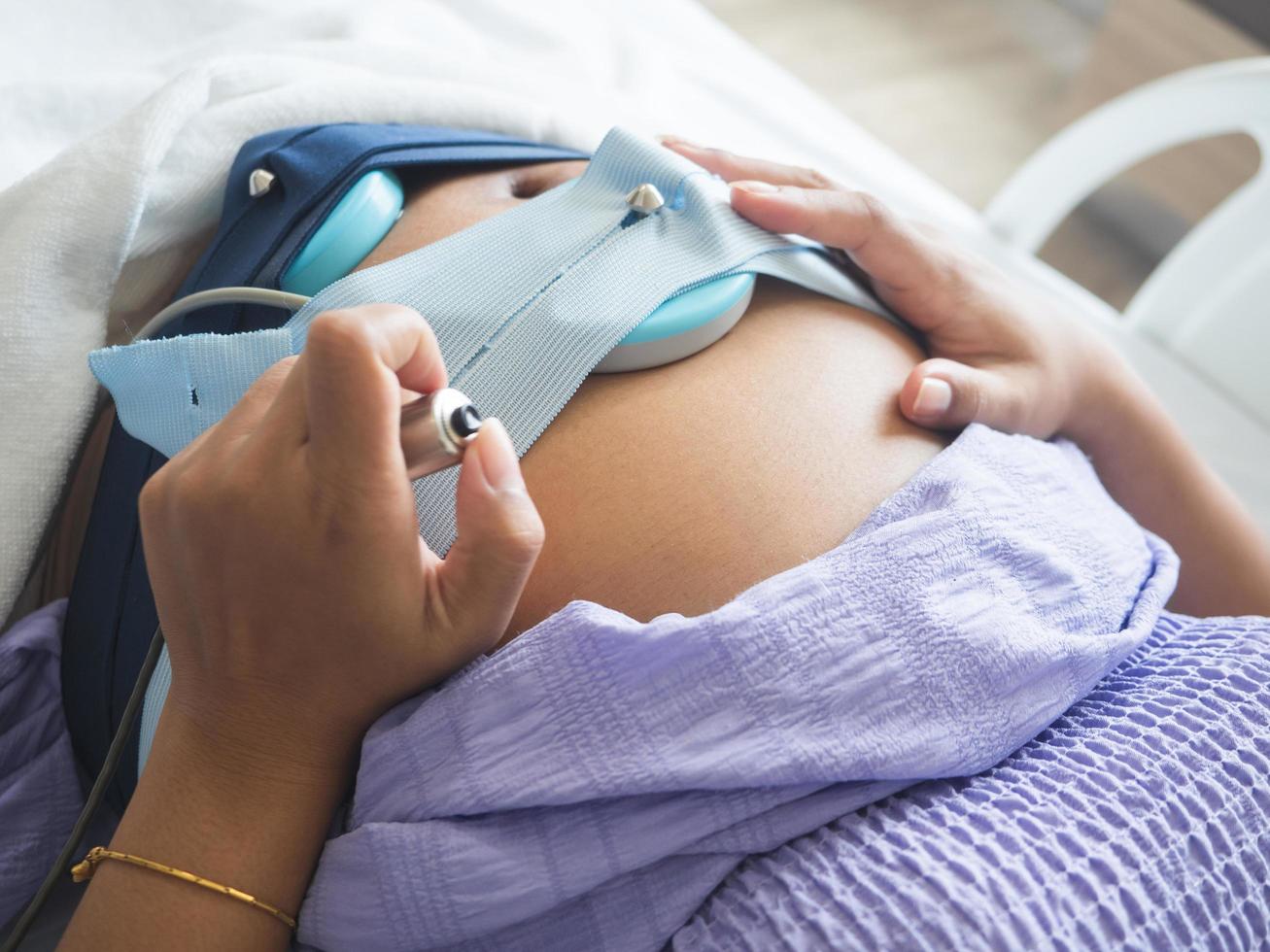 mulher grávida segurando interruptor médico para verificar o bebê na cama no hospital foto