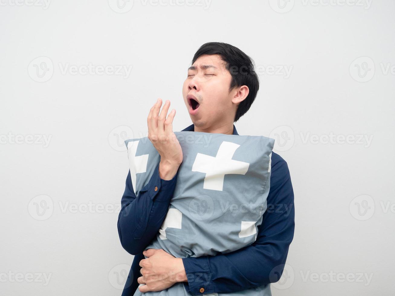 homem abraça travesseiro e boceja sentindo sonolento e fundo branco preguiçoso foto
