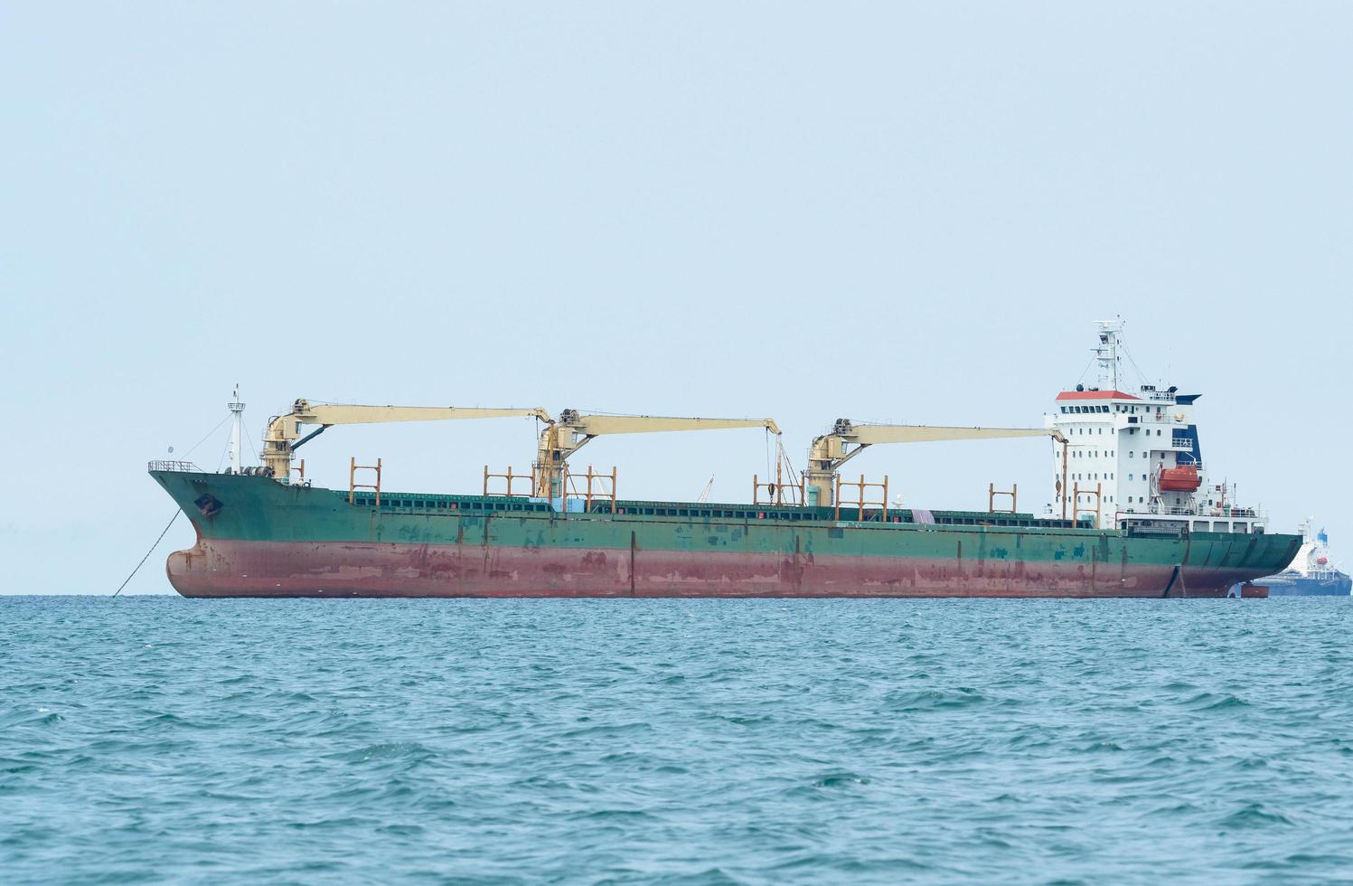 grande navio industrial com guindaste no oceano e céu azul, navio de carga para o conceito de transporte foto