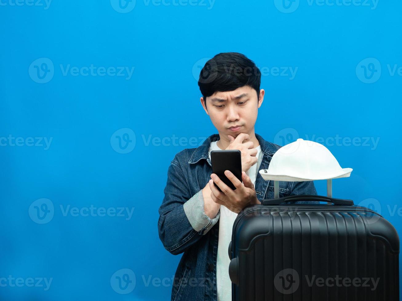 homem com gesto de bagagem pensando olhando para celular cópia espaço fundo azul foto