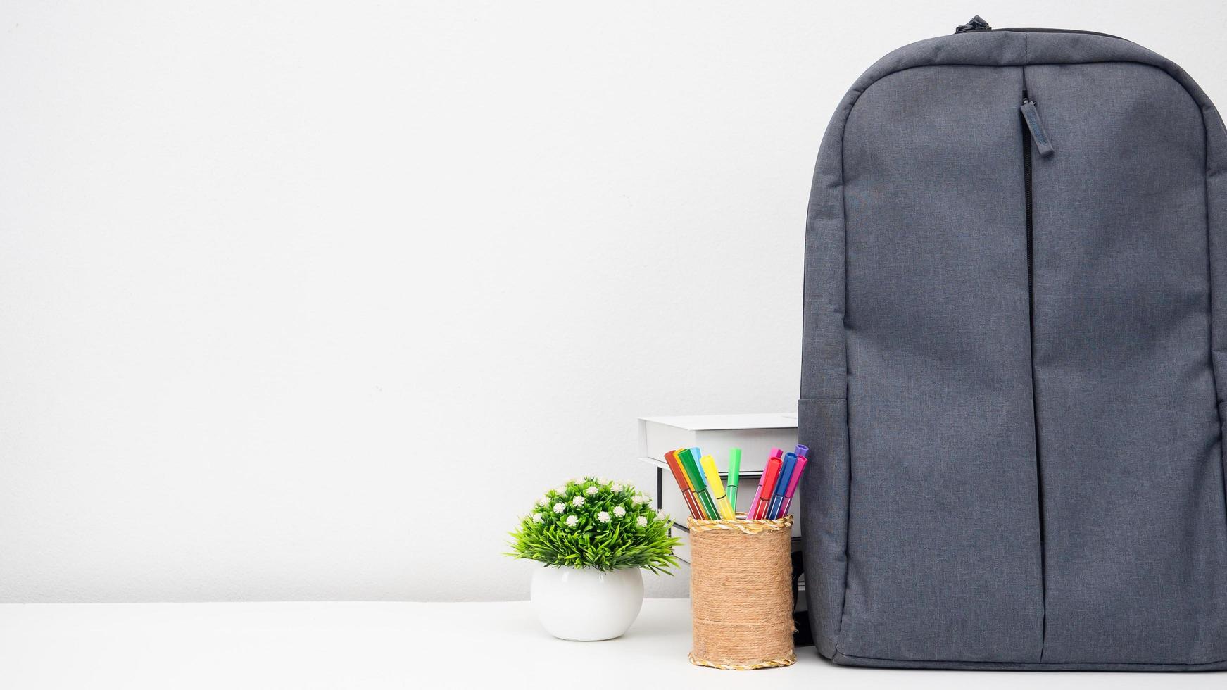 mochila escolar com caixa de lápis e livros sobre a mesa espaço de cópia de fundo branco foto