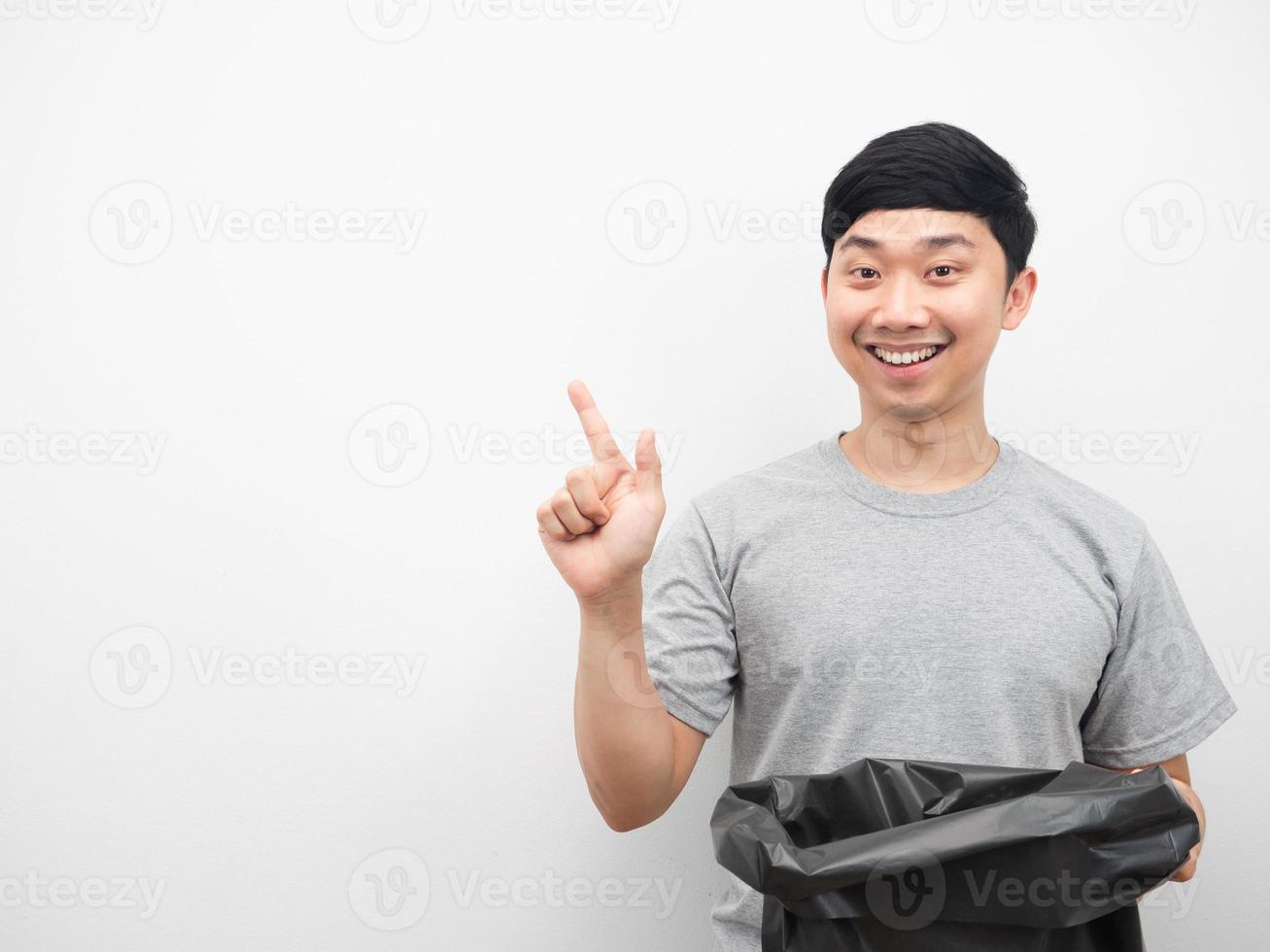 homem segurando lixo sorrindo e apontando o dedo para o espaço da cópia foto