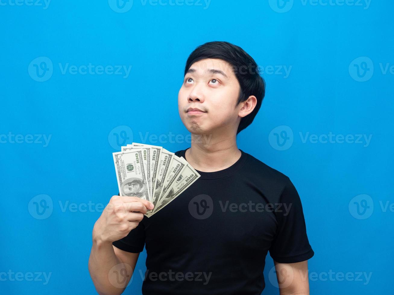 homem mostra dinheiro na mão e olhando para cima fundo azul foto