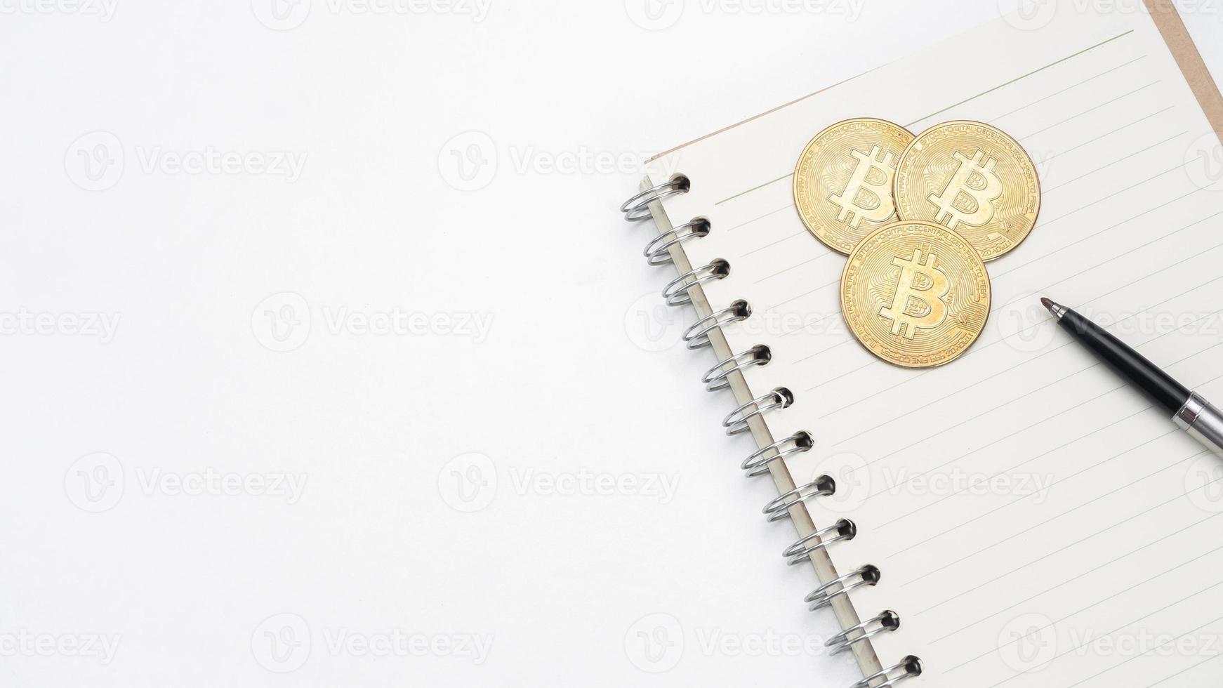 bitcoin com caneta no caderno de página em branco no espaço de cópia da vista superior da mesa foto