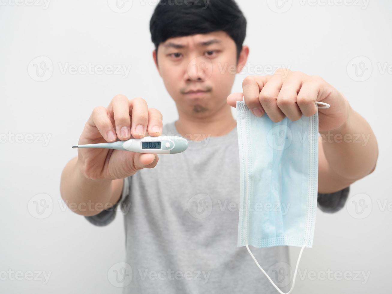 homem segurando termômetro com máscara de proteção retrato fundo branco foto