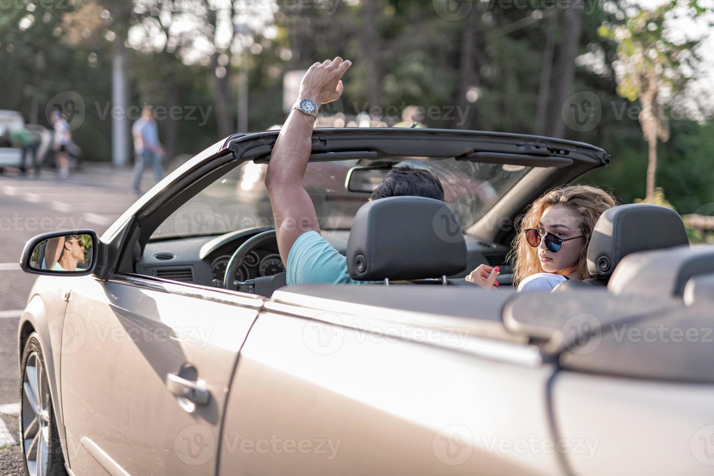 amigos se divertindo na viagem de carro ao redor do mundo. casal apaixonado com os braços para cima em um carro conversível. foto
