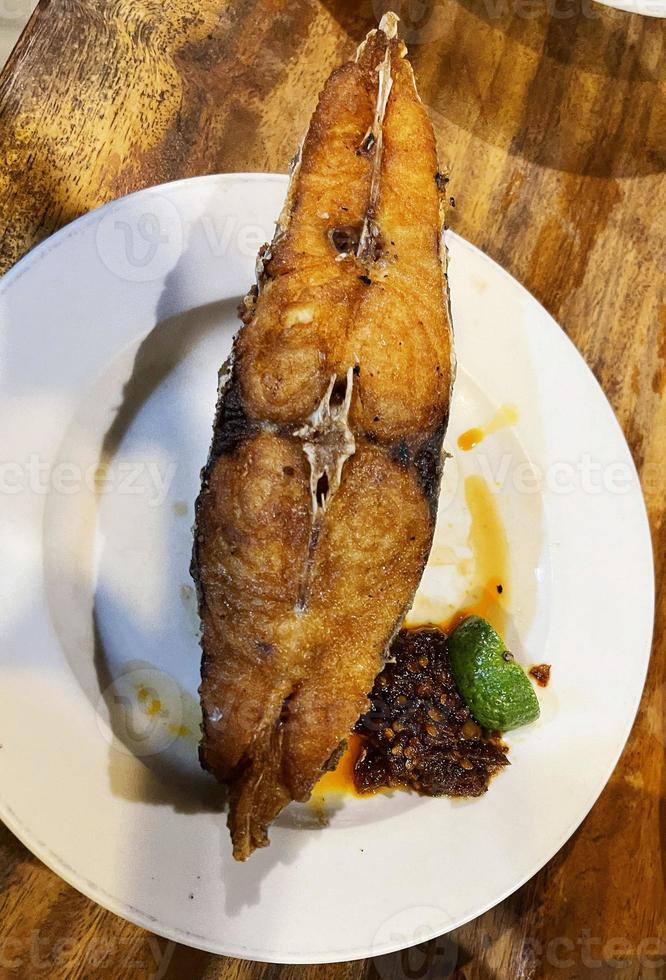 delicioso peixe cavala frito com molho picante e frutas cítricas, servido na chapa branca foto