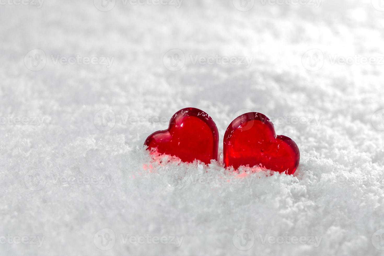 dois corações vermelhos mentem na neve fofa branca no símbolo de inverno do amor dia dos namorados foto