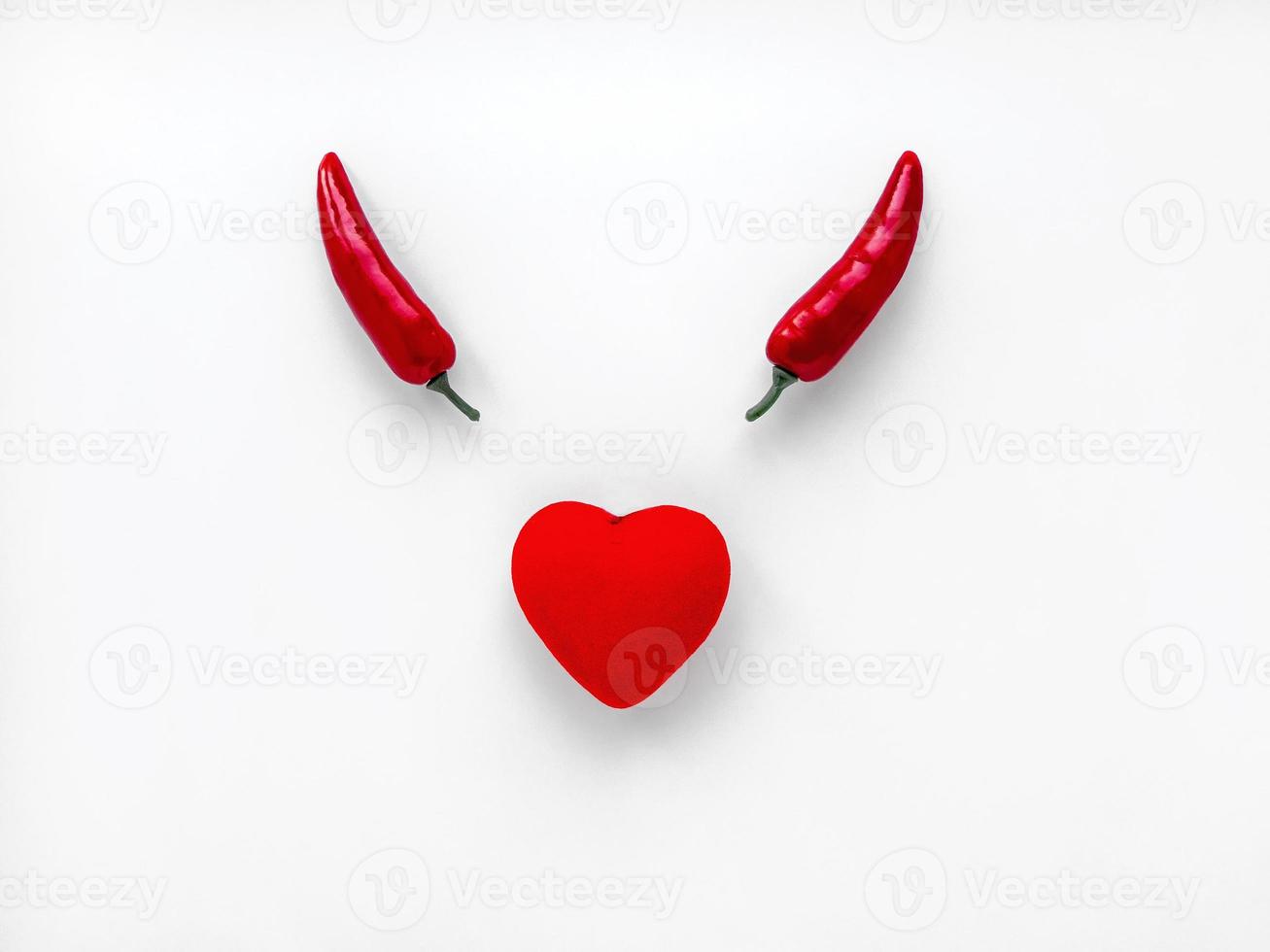 conceito de dia dos namorados. duas pimentas vermelhas e um coração em um símbolo do diabo de fundo branco isolado, travessura foto