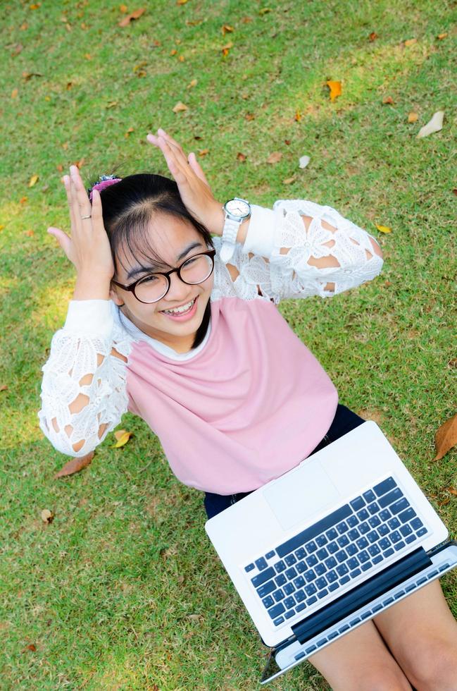 linda garota está feliz com o notebook na grama foto