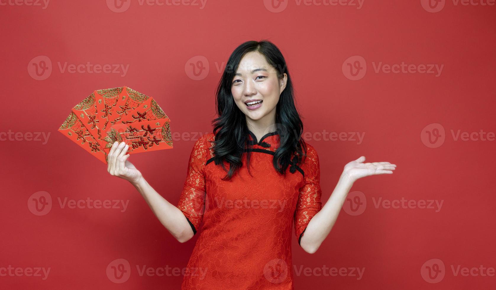 mulher asiática segurando o envelope da fortuna de dinheiro vermelho abençoando a palavra chinesa, o que significa que você pode ter muita sorte e grande lucro isolado em fundo vermelho para o conceito de celebração do ano novo chinês foto