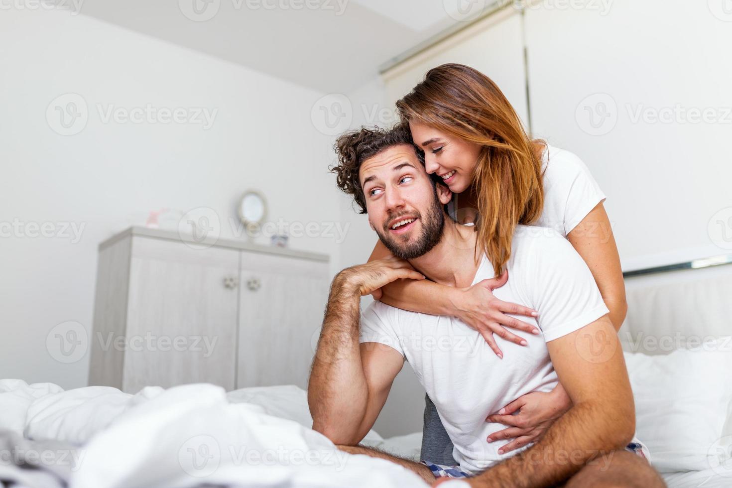 mulher abraçando seu parceiro na cama, casal feliz na cama mostrando emoções e amor. lindo casal apaixonado beijando na cama. lindo casal jovem deitado juntos na cama. foto