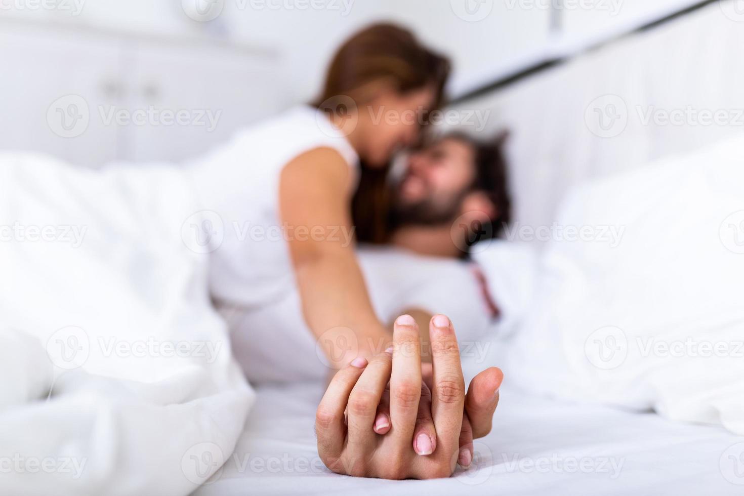 casal romântico na cama desfrutando de preliminares sensuais. concentre-se nas mãos de homem e mulher. feliz casal jovem sensual deitado na cama juntos foto