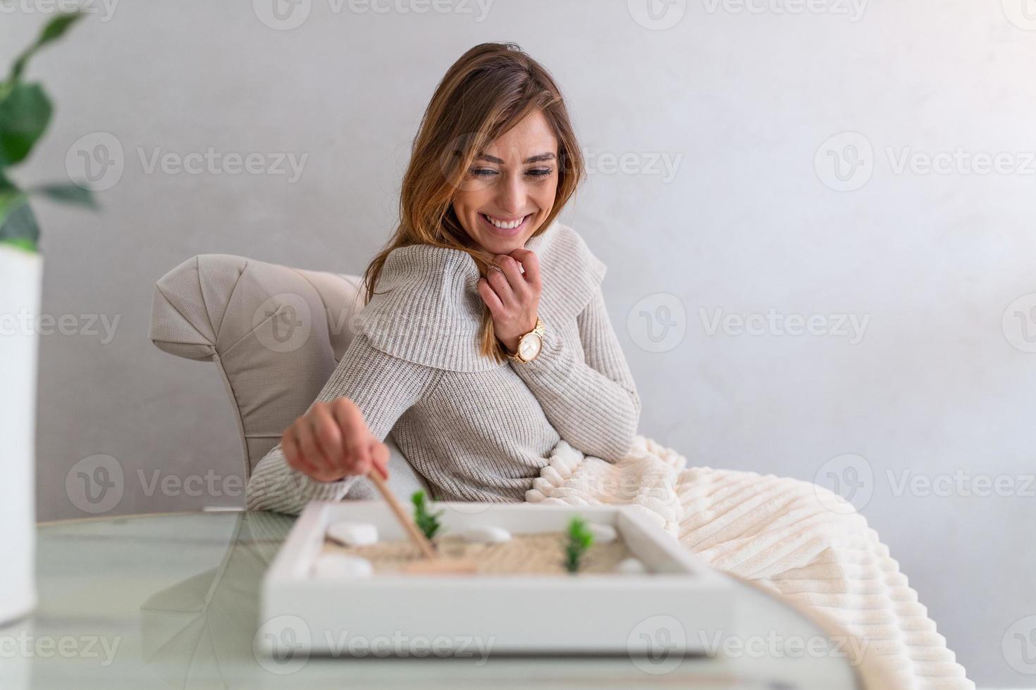 jovem feliz desfrutando de seu jardim zen em casa, adolescente alegre usando seu pequeno jardim zen e relaxando na sala de estar foto