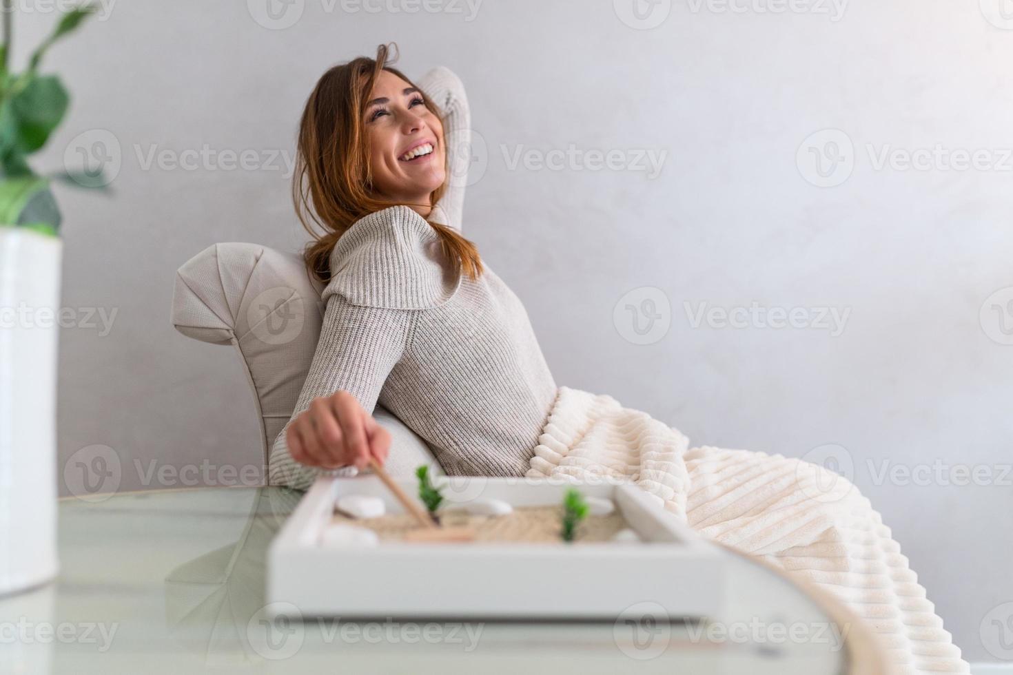 retrato de mulher jovem e bonita usando seu jardim zen em casa. linda jovem sorridente relaxando com seu jardim zen e aproveitando o dia foto