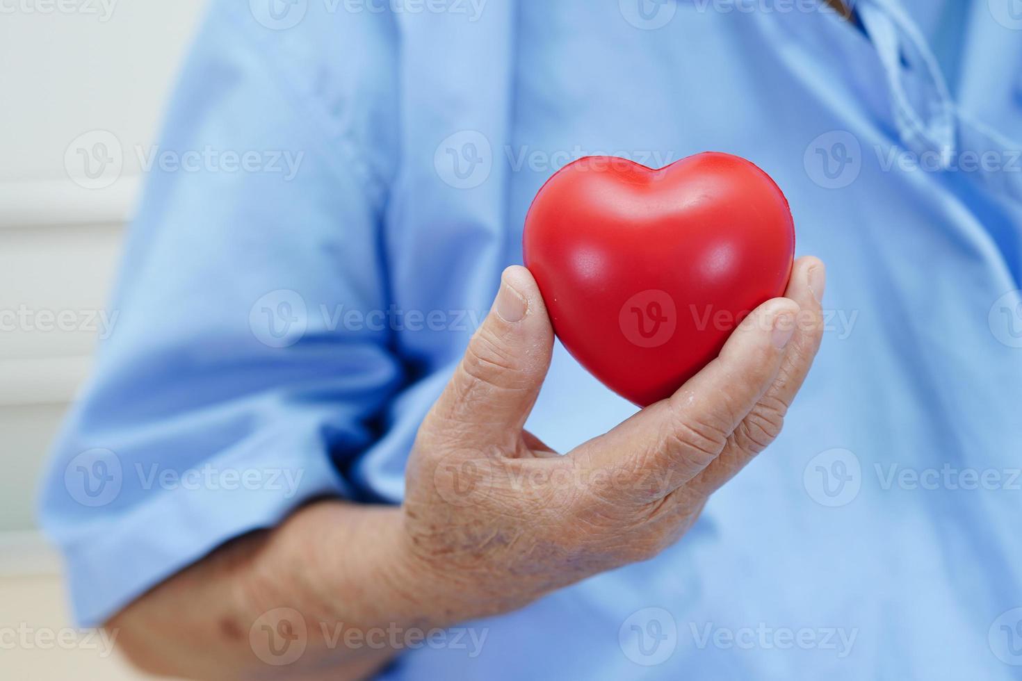 paciente asiática idosa idosa segurando coração vermelho no hospital. foto