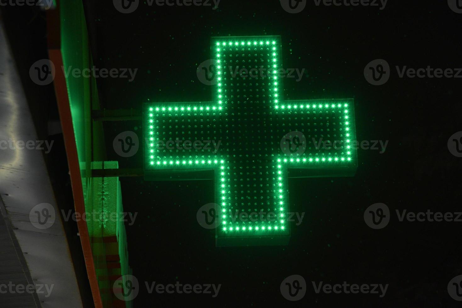 farmácias cruz verde à noite na cidade. brilhando com lâmpadas led, a cruz verde do hospital. foto