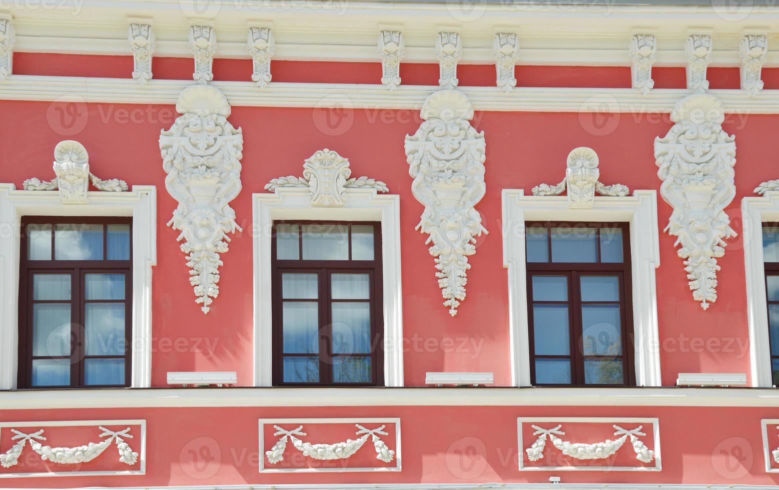 janelas linda casa rosa restaurada ornamentada com decorações de estuque branco. elemento de fachada do edifício. foto