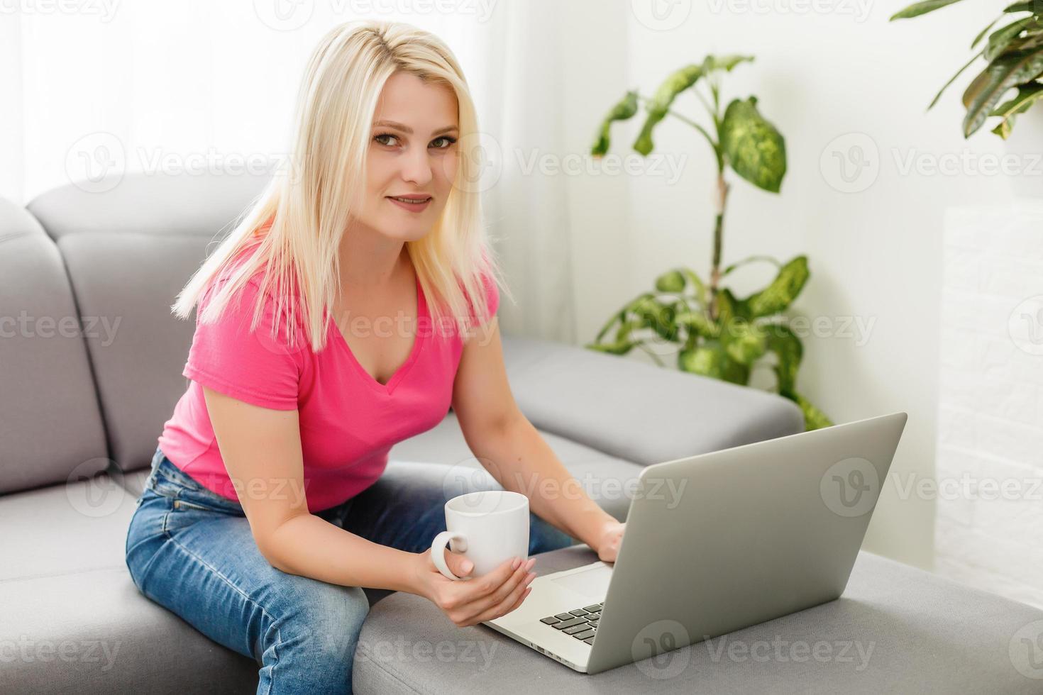 jovem mulher com laptop trabalha em casa foto