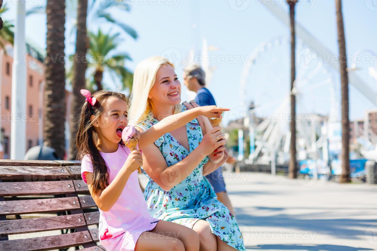 mãe e filha sentadas em um banco, observando o barco no mar do porto de genoa foto