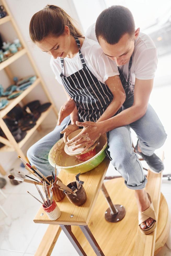 com o namorado ou marido. jovem ceramista feminina trabalha em ambientes fechados com produtos de argila feitos à mão. concepção de cerâmica foto